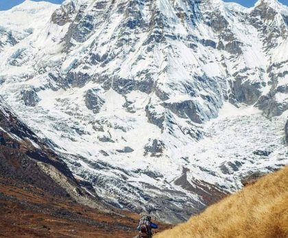 Trekker hiking on the Annapurna Base Camp Trek trail with breathtaking Himalayan mountain views in Nepal.