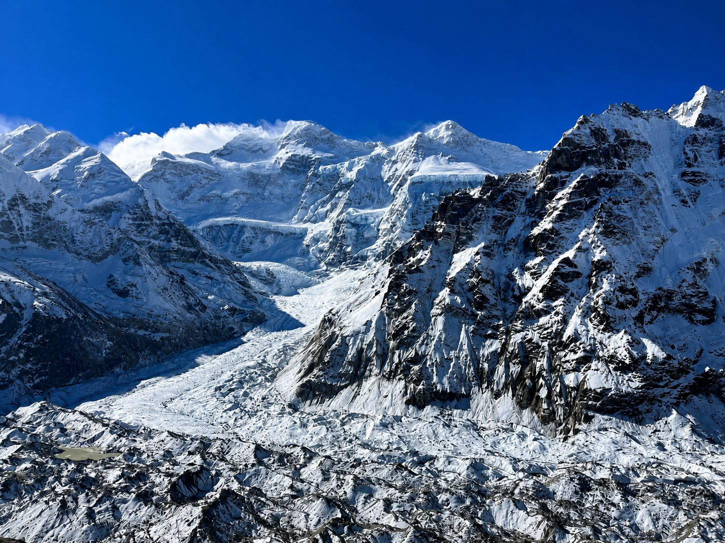 Split landscape showing snowy Himalayan glaciers and colorful autumn valleys along the Kanchenjunga Circuit Trek.