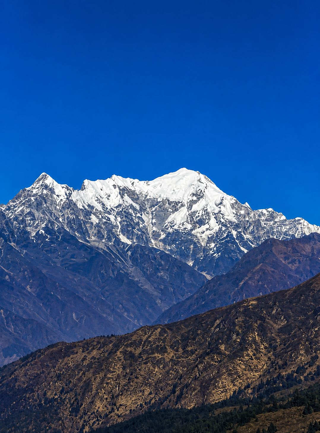 Panoramic view of the snow-capped Himalayan peaks near Gosainkunda under a clear blue sky in Langtang National Park, Nepal.